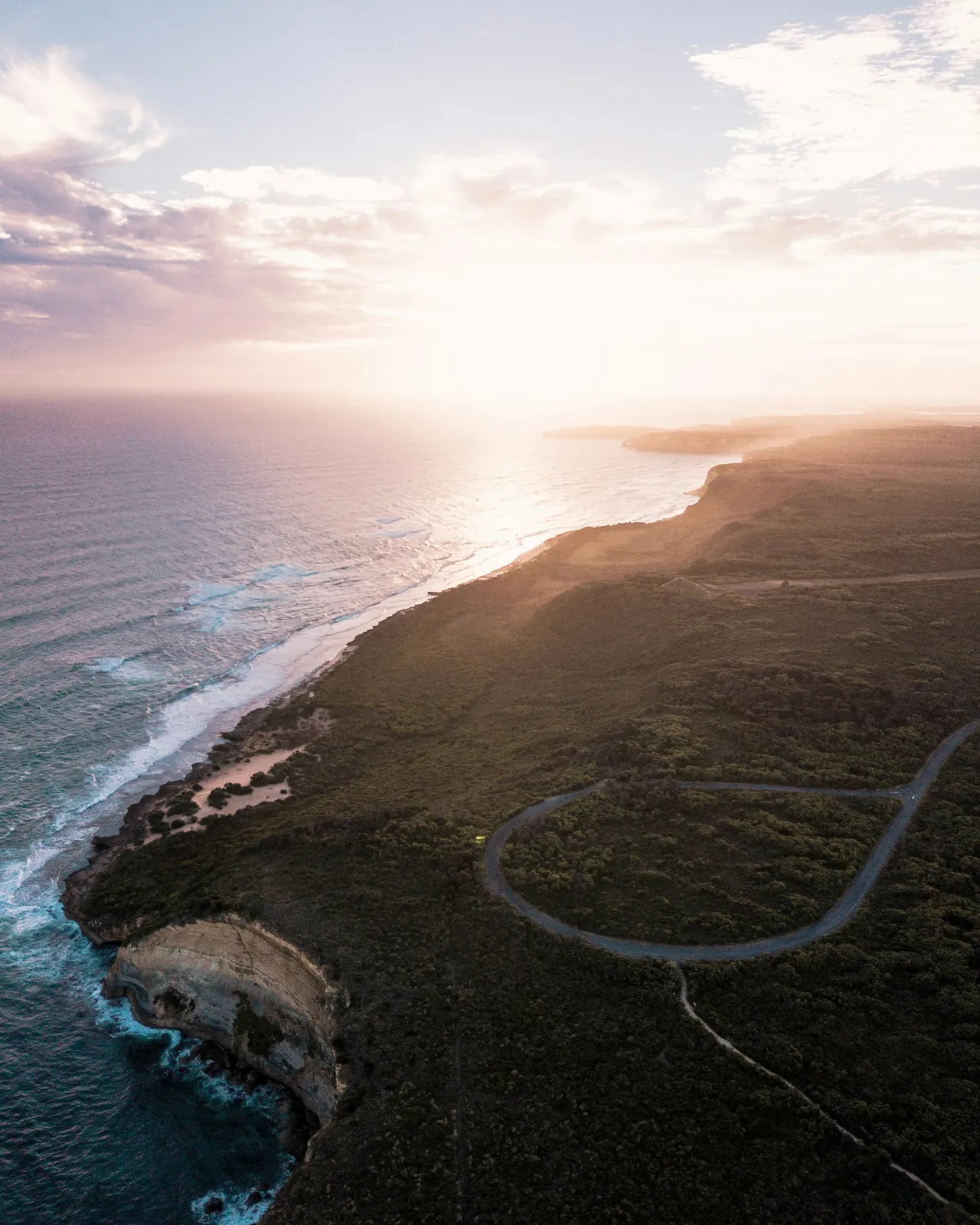 Aerial view of a winding coastal road and cliffs near Anglesea, Victoria, in evening light.