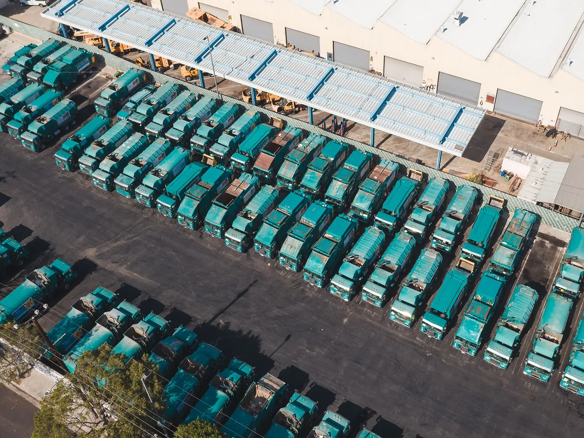 An aerial view of a large fleet of teal trucks parked in neat rows.